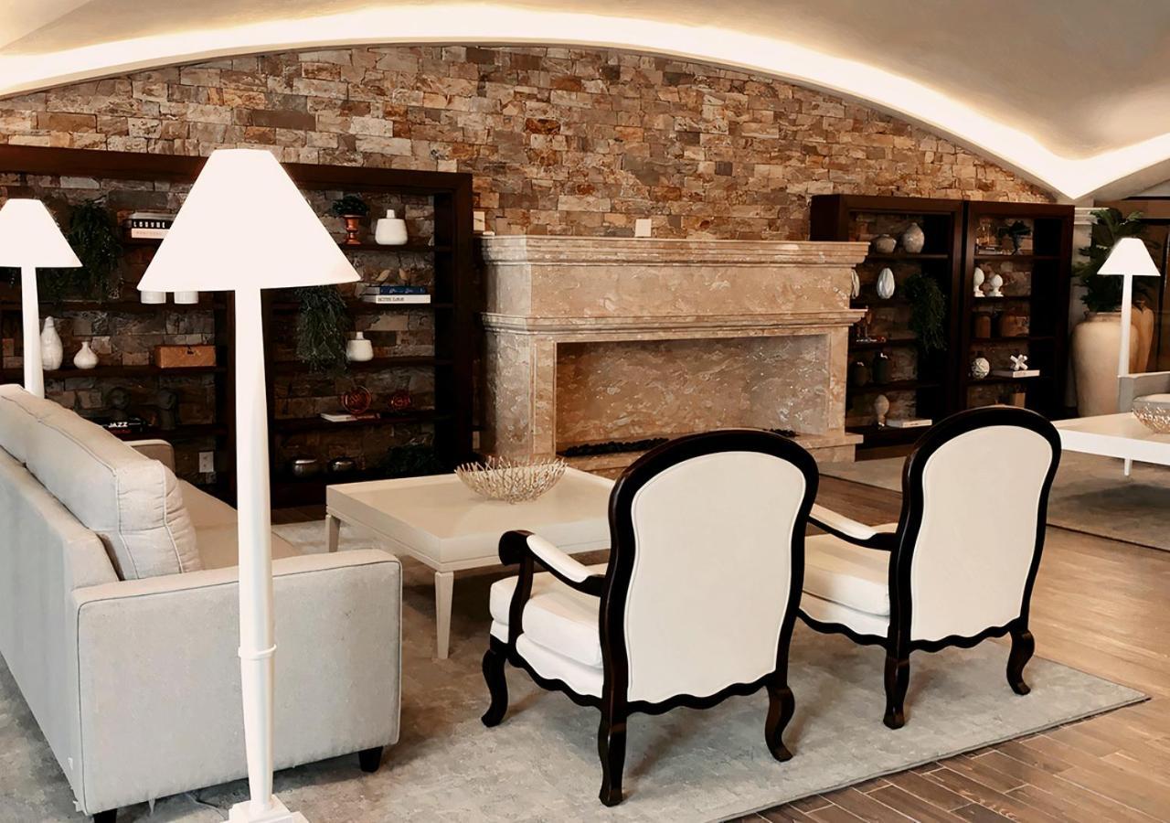Buona Vitta Gramado Resort & Spa By Gramado Parks エクステリア 写真 The photo shows a stylish living room with a modern design. In the center, there is a light-colored sofa and two elegant white armchairs with black wooden frames. A coffee table is placed in front of the sofa. Behind them, there is a large, decorativ