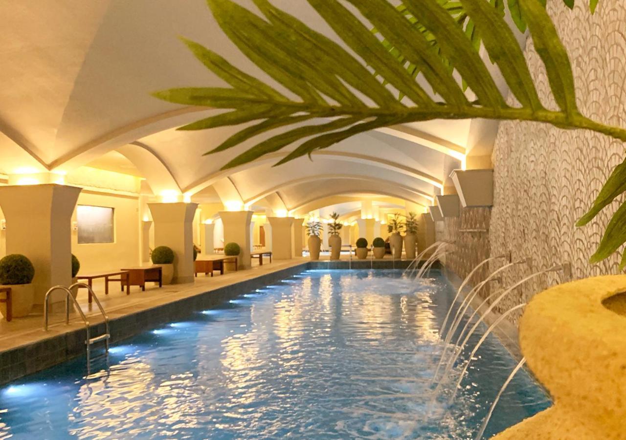 Buona Vitta Gramado Resort & Spa By Gramado Parks エクステリア 写真 The photo shows an indoor swimming pool with a serene and elegant atmosphere. The pool has a calm blue water surface, illuminated by soft lights along its edges. The architectural design features arches in the ceiling, creating an open and spacious f