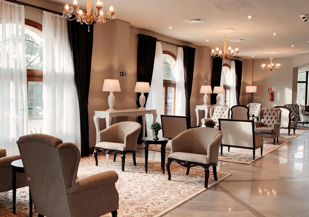 Buona Vitta Gramado Resort & Spa By Gramado Parks エクステリア 写真 The photo depicts a stylish and sophisticated lounge area. It features several elegant chairs and sofas, arranged around small tables on a decorative rug. The room is well-lit with natural light coming in through large windows dressed with flowing wh