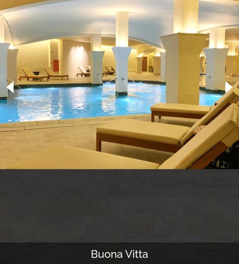 Buona Vitta Gramado Resort & Spa By Gramado Parks エクステリア 写真 The photo shows a tranquil indoor pool area, featuring a large swimming pool with clear blue water. Surrounding the pool are several lounge chairs made of light-colored wood, positioned for relaxation. The space is well-lit, with soft lighting highli