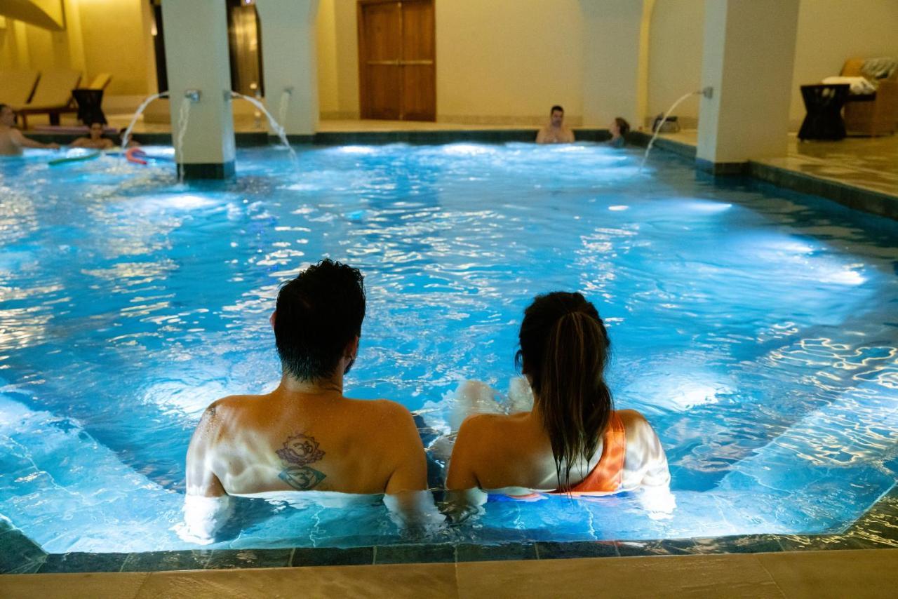 Buona Vitta Gramado Resort & Spa By Gramado Parks エクステリア 写真 The photo shows a couple sitting in a swimming pool with gentle lighting. They are facing away from the camera, appearing relaxed and enjoying their time together. The water is illuminated with a soft blue light, creating a serene atmosphere. In the 