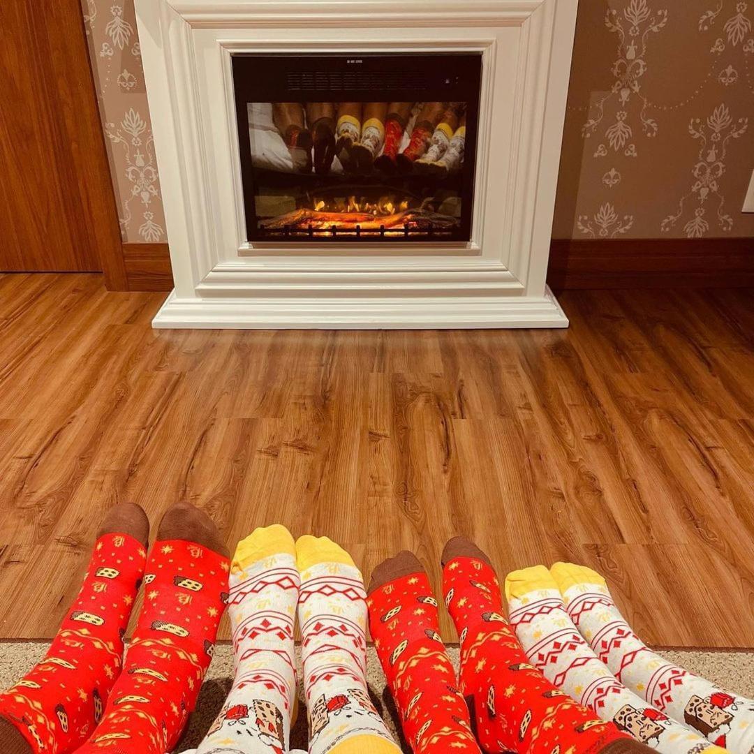 Buona Vitta Gramado Resort & Spa By Gramado Parks エクステリア 写真 The photo shows a cozy indoor setting with a warm fireplace. In the foreground, several pairs of feet are displayed, each wearing brightly colored socks with various patterns. The socks include red, yellow, and white designs, contributing to a cheerf