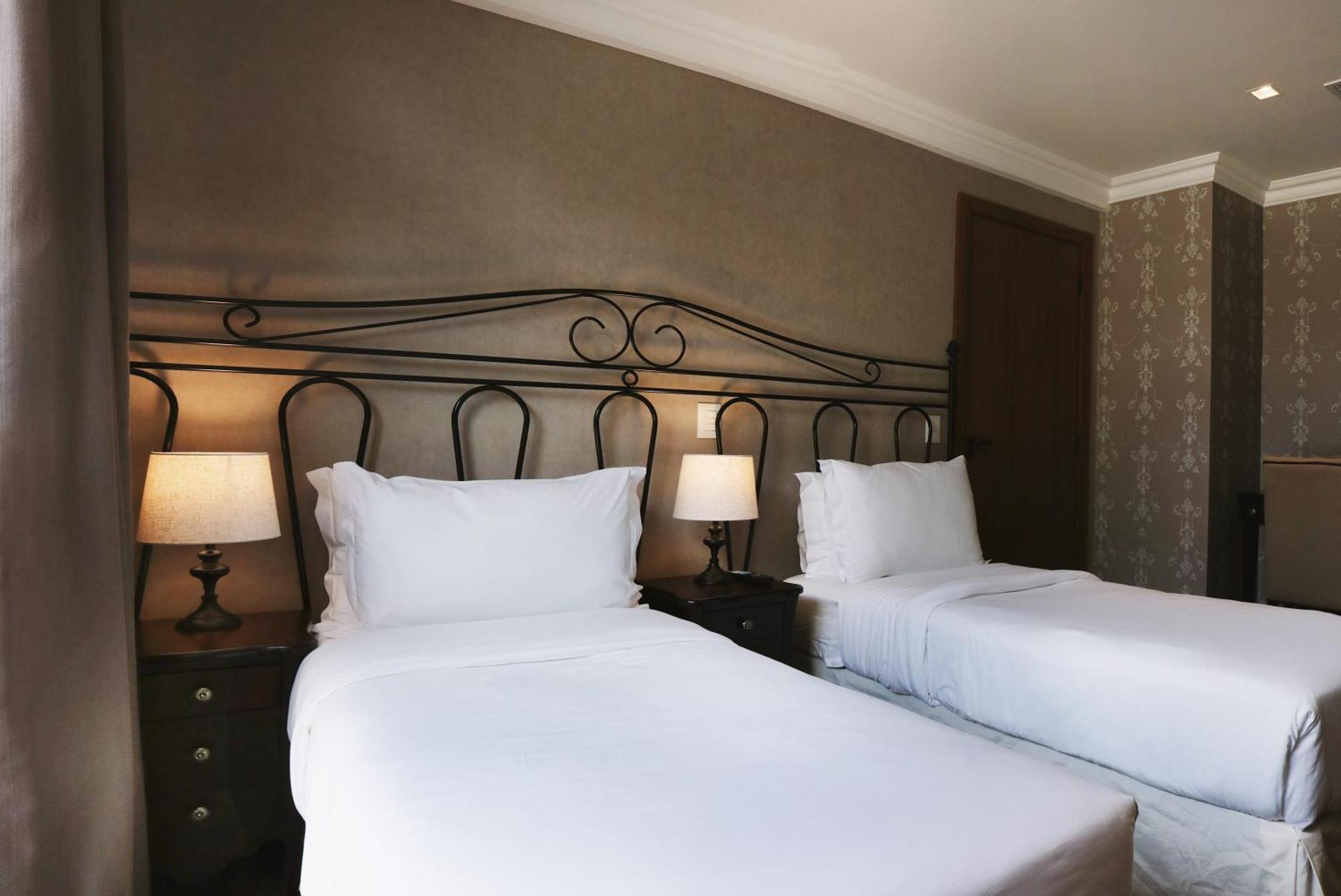 Buona Vitta Gramado Resort & Spa By Gramado Parks エクステリア 写真 The photo shows a neatly arranged hotel room featuring two single beds with white bedding. The beds have decorative metal headboards, and there are bedside tables on either side with lamps. The room's walls have a subtle design, and there is a door v