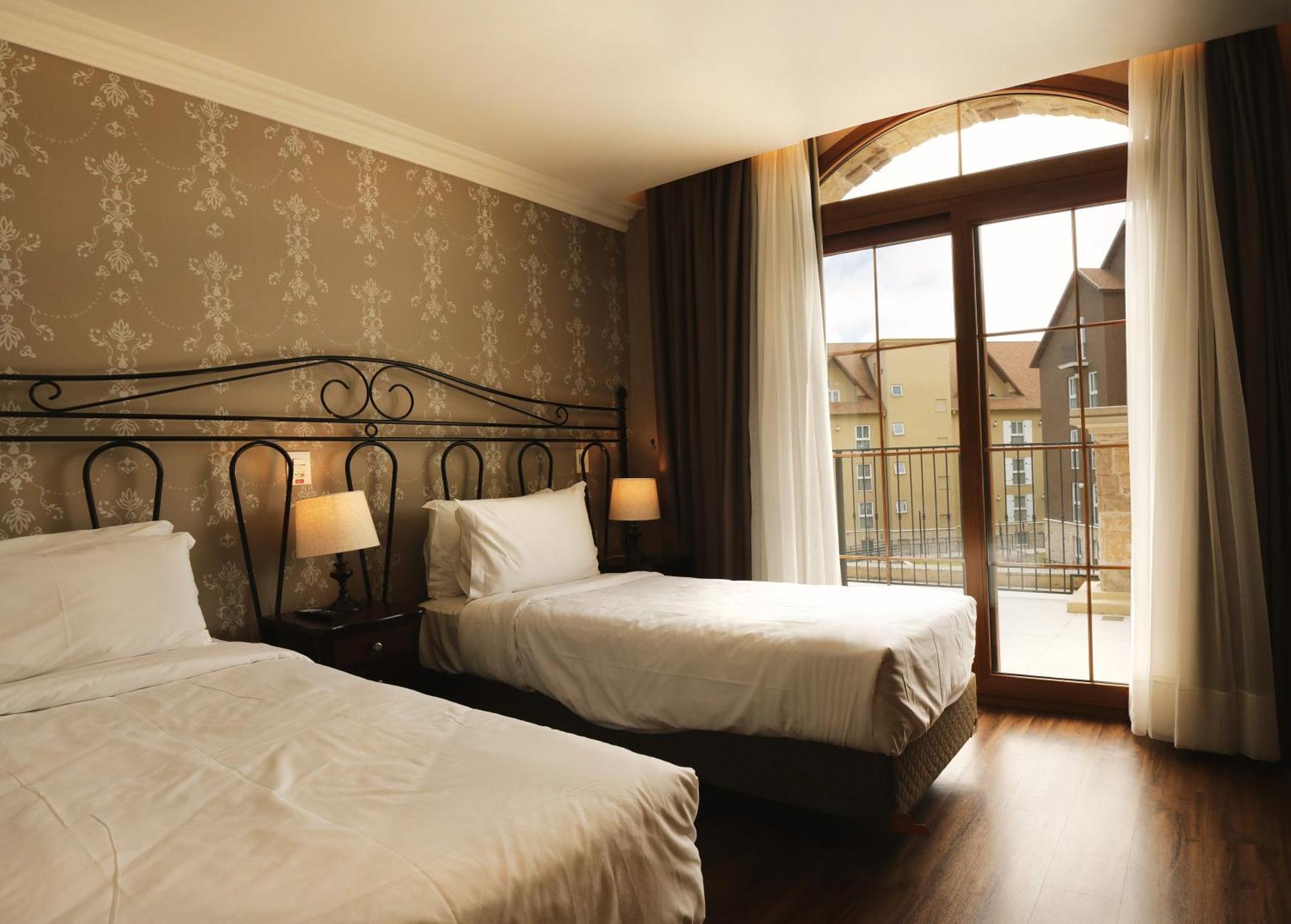 Buona Vitta Gramado Resort & Spa By Gramado Parks エクステリア 写真 The photo shows a well-decorated hotel room featuring two beds. One bed is larger, likely a double bed, while the other is a single bed. The walls are adorned with a floral pattern, and there are bedside lamps next to the larger bed. Large windows wi