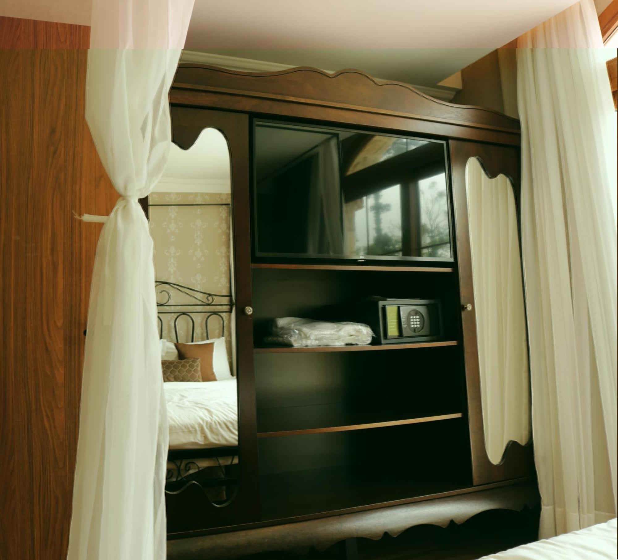 Buona Vitta Gramado Resort & Spa By Gramado Parks エクステリア 写真 The image shows a wooden cabinet with a television mounted on the front. The cabinet has decorative edges and is paired with sheer white curtains on either side. Inside the cabinet, there are shelves, and a small safe or storage box is visible on one