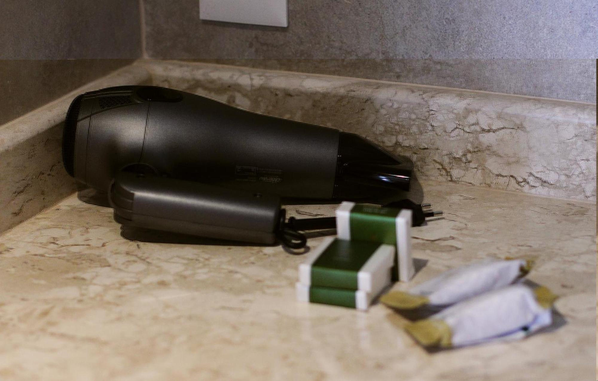 Buona Vitta Gramado Resort & Spa By Gramado Parks エクステリア 写真 The photo shows a black hairdryer placed on a marble countertop. Next to the hairdryer, there are two wrapped items, likely toiletries, with green and white packaging. Additionally, there are two more items, also wrapped, which appear to be in simila