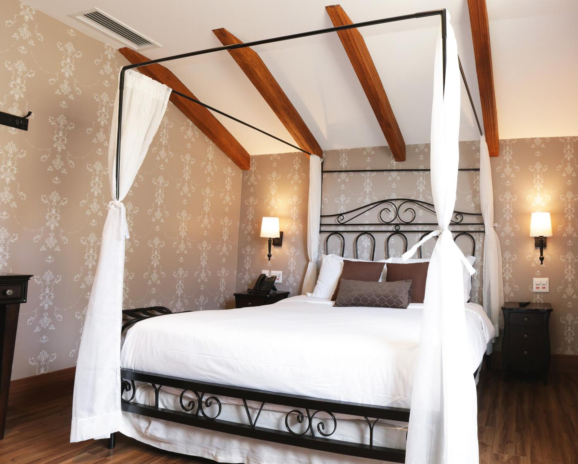 Buona Vitta Gramado Resort & Spa By Gramado Parks エクステリア 写真 The photo shows a beautifully designed bedroom featuring a four-poster bed with a metal frame and flowing white curtains. The bed is adorned with white bedding and brown decorative pillows. The room has wooden beams on the ceiling and is decorated wi