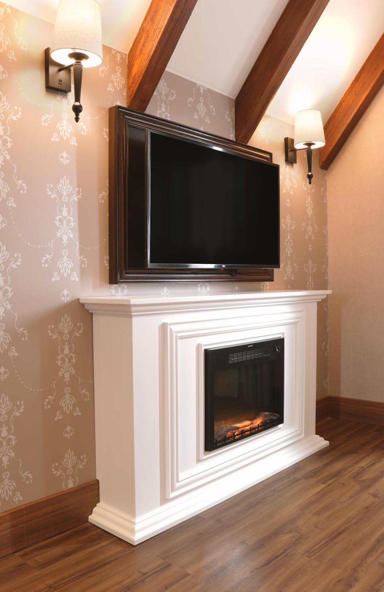 Buona Vitta Gramado Resort & Spa By Gramado Parks エクステリア 写真 The image shows a modern living room setup featuring a white mantel with an electric fireplace. Above the mantel, there is a large flat-screen television mounted on the wall. The fireplace has a glass front and displays a realistic flame effect, crea