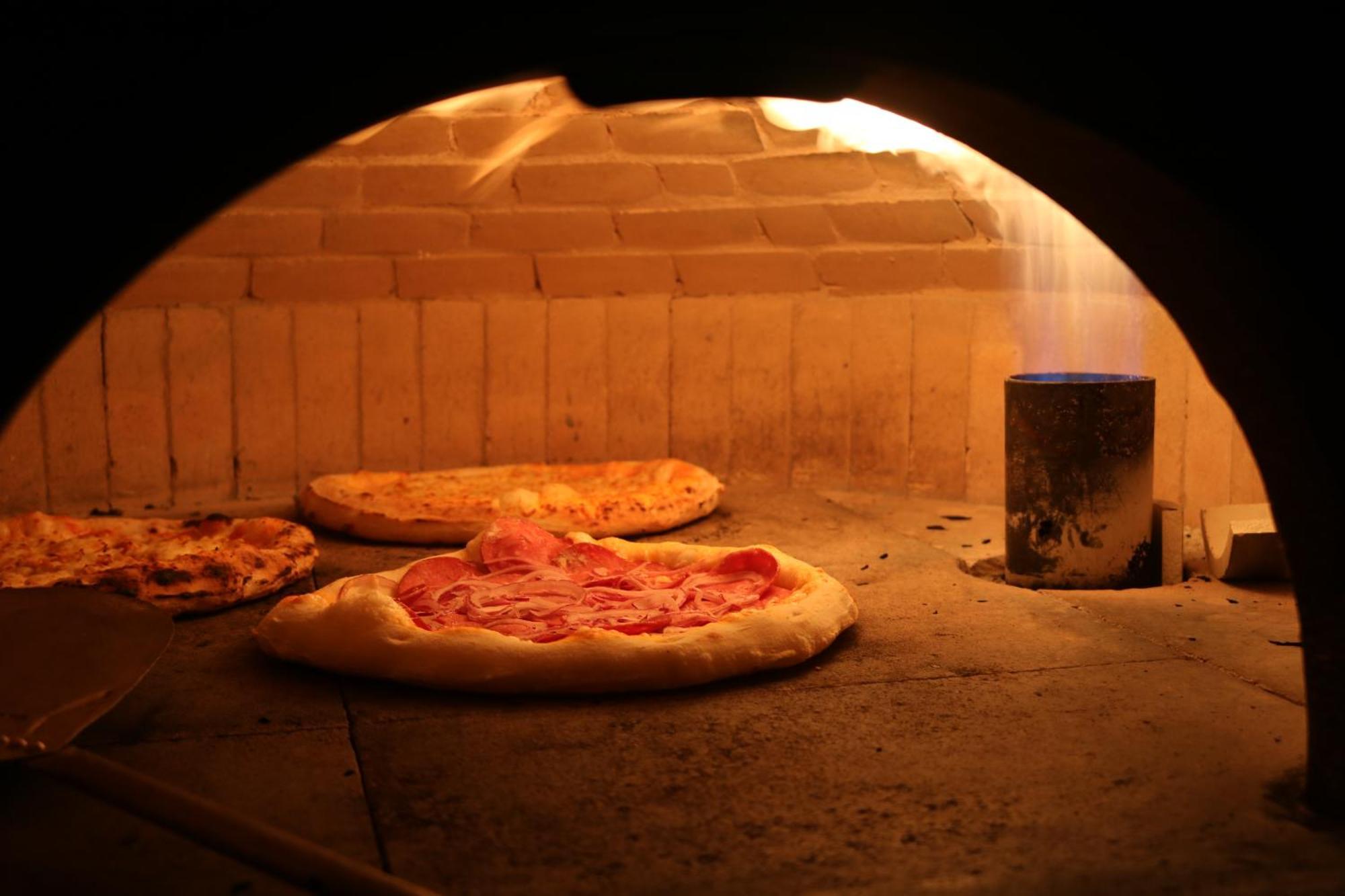 Buona Vitta Gramado Resort & Spa By Gramado Parks エクステリア 写真 The photo shows a traditional pizza oven. Inside the oven, there are several pizzas placed on the stone surface. The pizzas appear to have various toppings, including what looks like cheese and possibly pepperoni. The oven has a warm, glowing ambianc