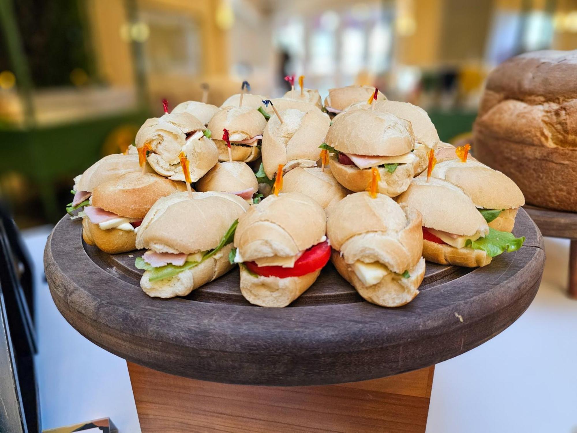 Buona Vitta Gramado Resort & Spa By Gramado Parks エクステリア 写真 The photo shows a platter of small sandwiches, likely sliders, arranged neatly on a wooden serving tray. These sandwiches have various fillings, including what appears to be ham, lettuce, and tomato. They are garnished with colorful toothpicks, and t